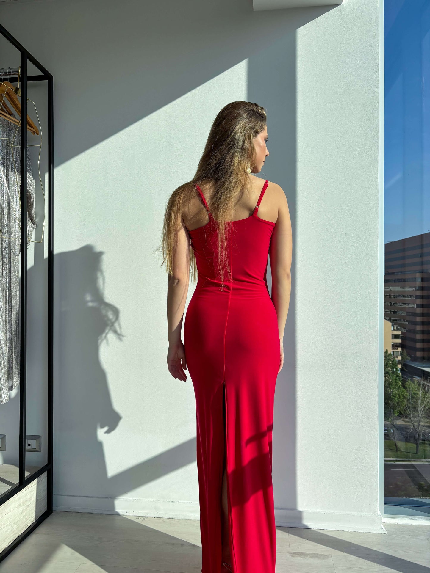 Mujer luciendo el Vestido Greta rojo, elegante y largo con corte sirena y tajo en la pierna, ideal para eventos formales.