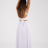 Mujer luciendo un elegante vestido blanco largo en una pose relajada, ideal para bodas civiles y ceremonias en la playa.