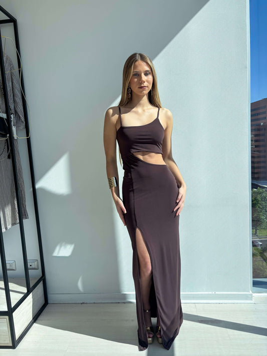Mujer luciendo un vestido de fistes asimetrico cafe con abertura en el abdomen y detalles elegantes.